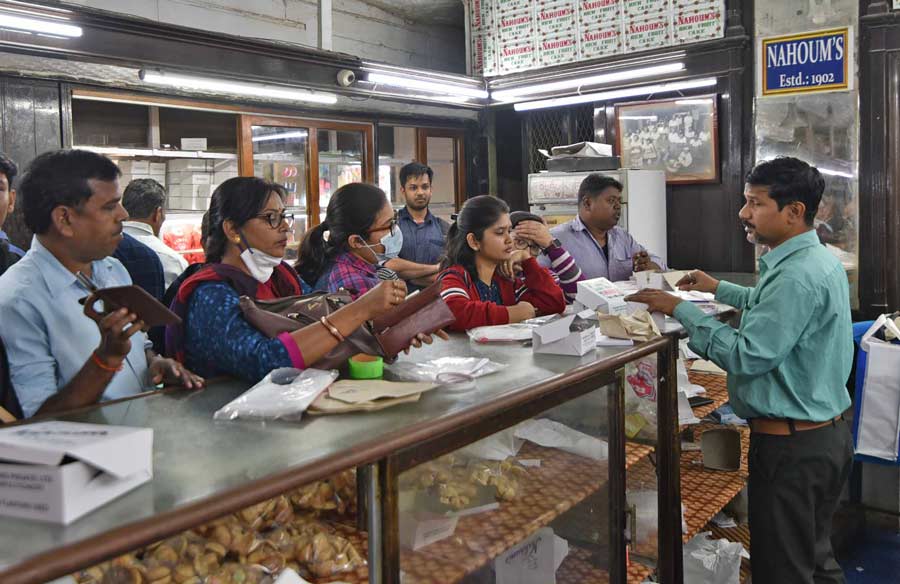 People purchase cakes and baked items at Nahoum’s at New Market on Monday
