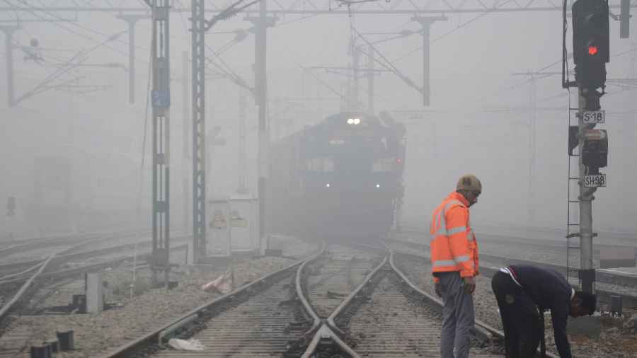 A train passes through a railway station amid low visibility due to dense fog on a cold winter morning, in Amritsar