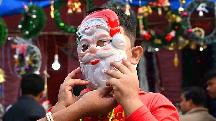 A boy wears a Santa Claus mask