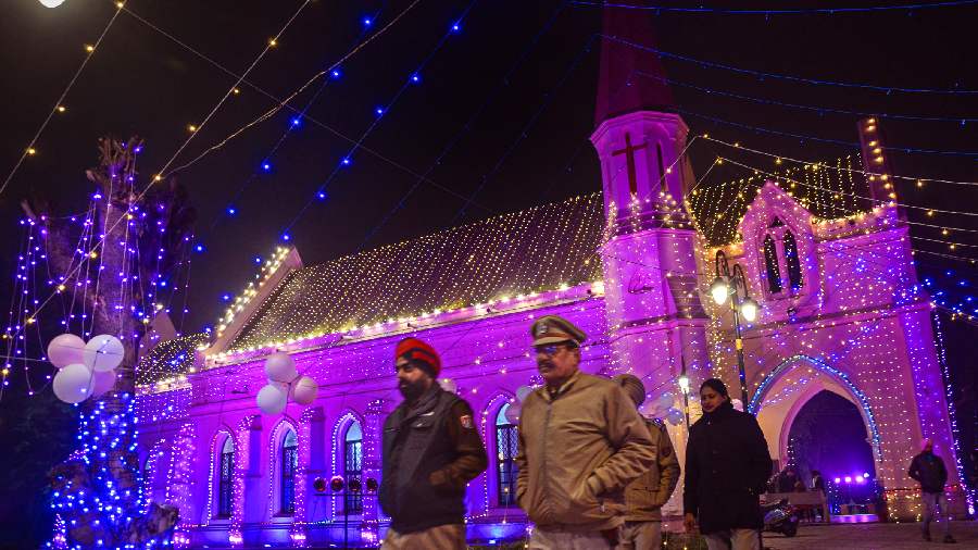 Security personnel walk in front of the illuminated St Paul's church ahead of Christmas celebrations in Amritsar.