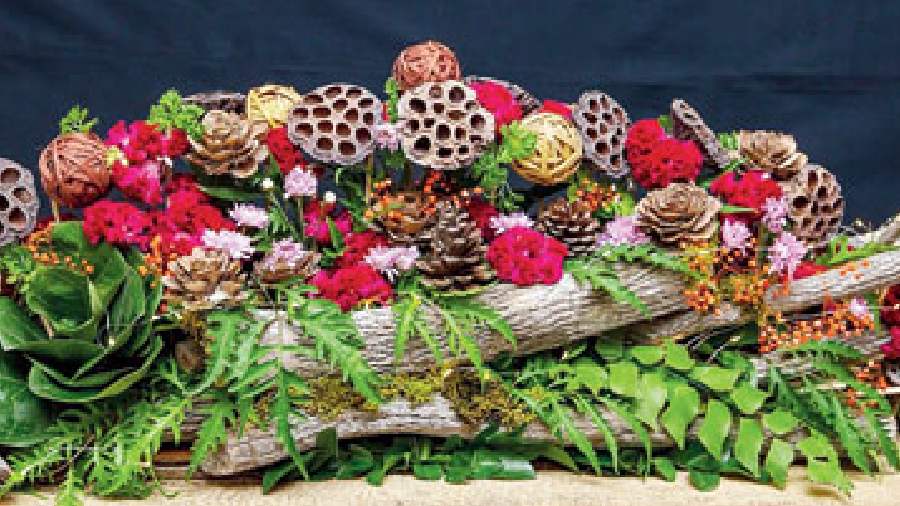 Flower shapes made with jackfruit leaves with dry wood branches, lotus pods, dry leaf bells (of different colours), arial leaves, kamini leaves, and multi-coloured baby chrysanthemum flowers.