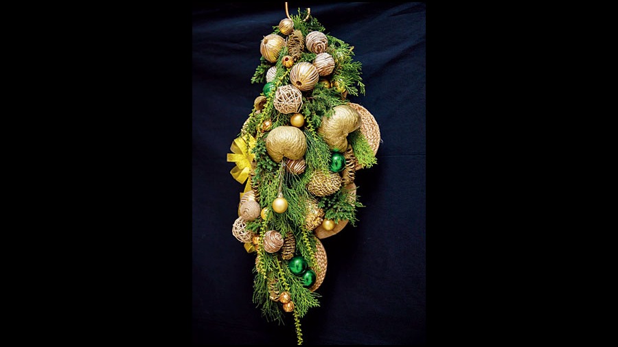 Jute cane base with junipers, thuja leaves, palms, green and gold Christmas balls and pine cones.