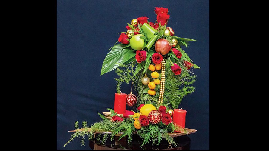 China pal, ferns, aralia and rose with Christmas bells and candles.