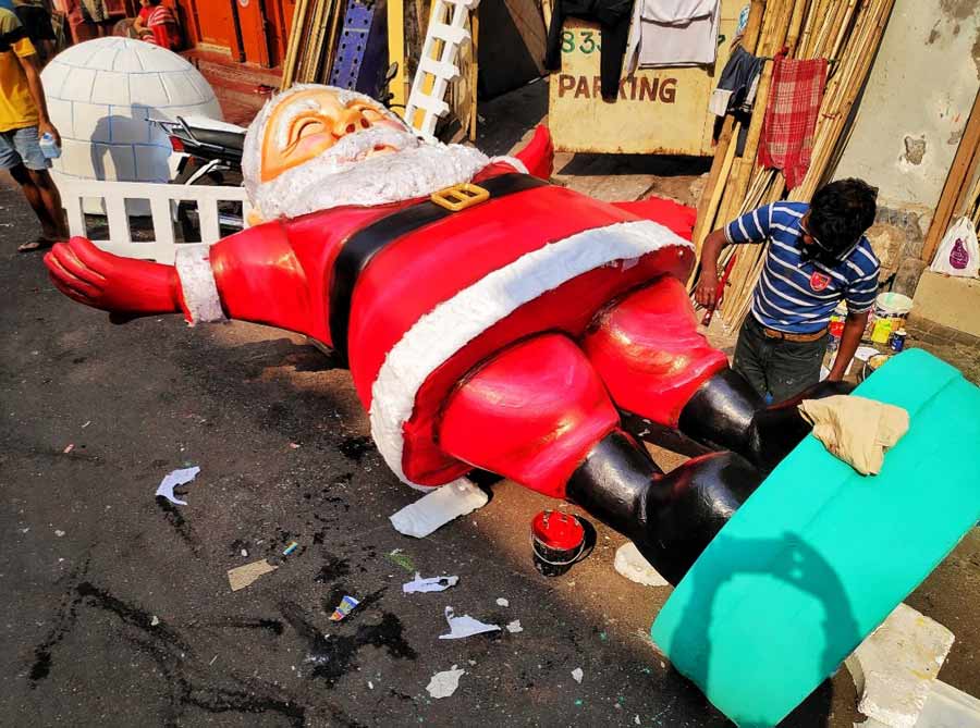 An artist puts finishing touches on a huge Santa Claus prop at Dompara on Saturday