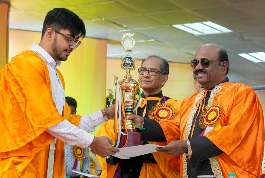 Jaydeep Nandy (L), receives the Asoke Kumar Sarma Memorial trophy for the best sportsperson of the year 2022 from West Bengal governor and chancellor of Jadavpur University, CV Ananda Bose, during the 65th Annual Convocation of the university on Saturday