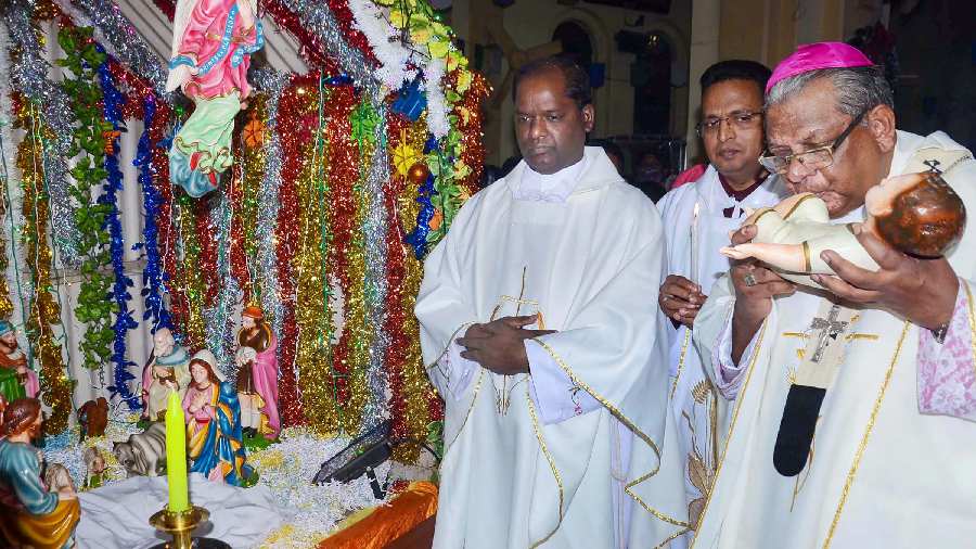 Archbishop Felix Toppo kisses the feet of Baby Jesus statue as he leads the Christmas midnight mass at St. Mary's Cathedral, in Ranchi. 