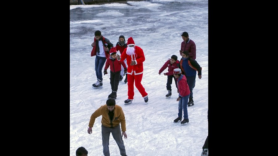  A man dressed as Santa Claus on Christmas skates with other students at an ice-skating rink at Lakkar Bazar in Shimla. 