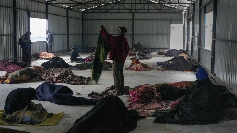  Homeless people wrapped in woolens sleep inside a shelter home. 