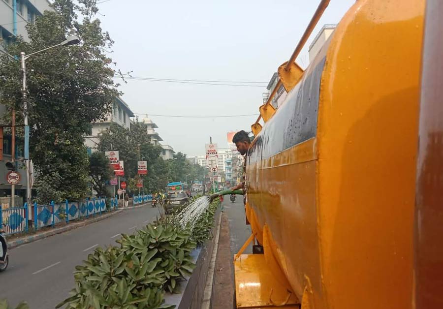 KMC workers water plants on road dividers in Kolkata. KMC organised the cleaning of the medians along Gariahat road, from Golpark to Panchanantala