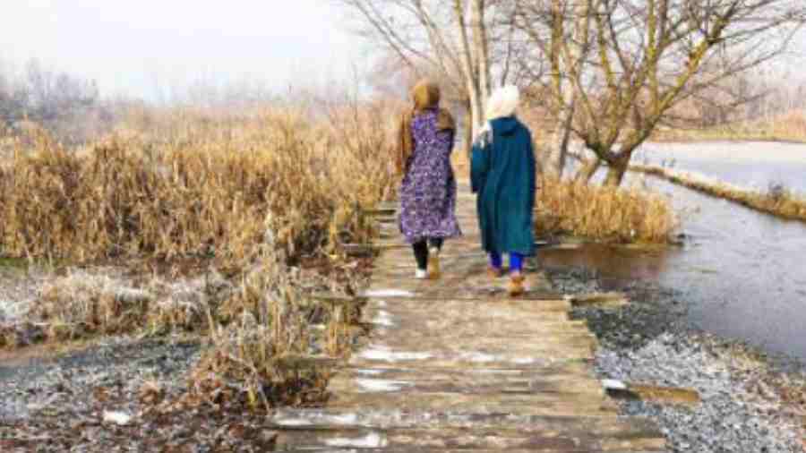 Women walk on a bridge over the partially frozen Dal Lake in Srinagar on Wednesday. The minimum temperature in Srinagar was -5.6°C, down from minus -4.8°C on Tuesday night, officials said. There is a possibility of intermittent light to moderate snowfall at scattered places over two days from Thursday, they added.