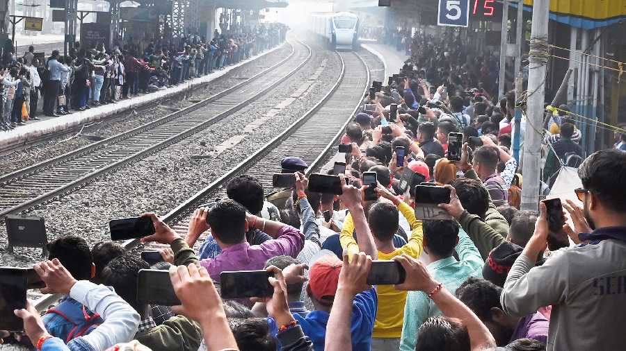 People take pictures as the Vande Bharat Express enters Belur station on Friday