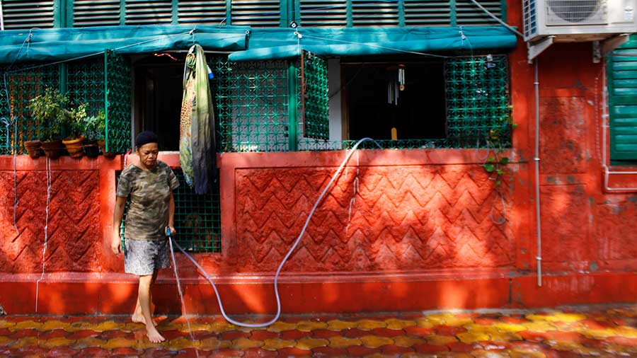 A resident of Bow Barracks washes the frontage of her house. 