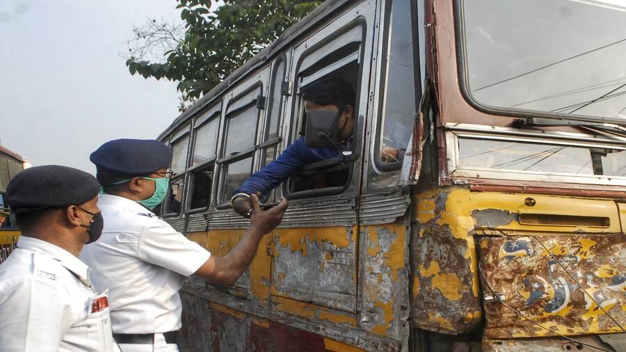 A policeman checks the papers of a mini bus from its driver in Kolkata on Tuesday.