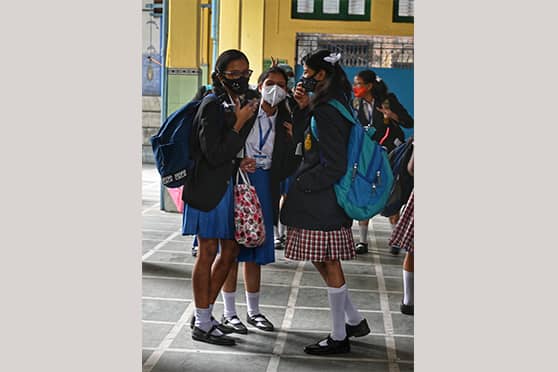 Students greet their friends with sparkling eyes and giggles behind masks at Holy Child Girls High School. 