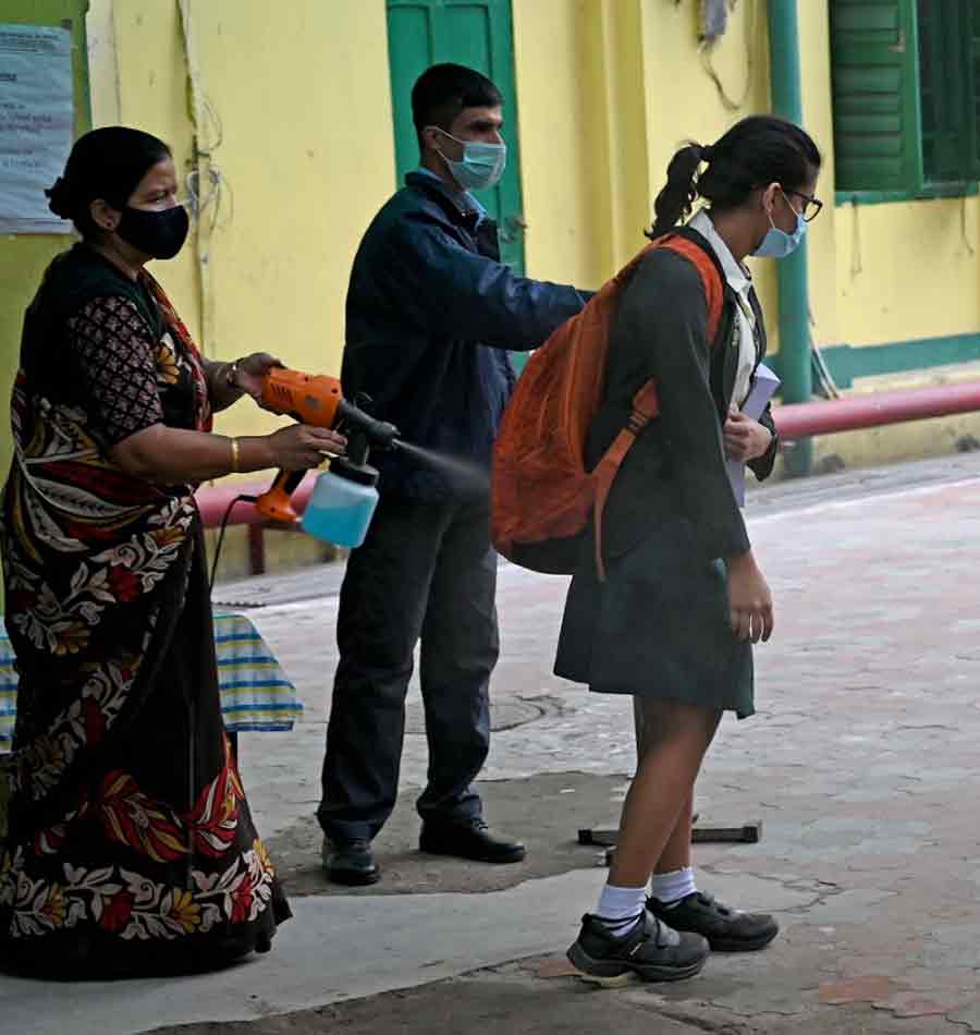 Staff at the Pratt Memorial School sanitise a student’s school bag before she enters the campus