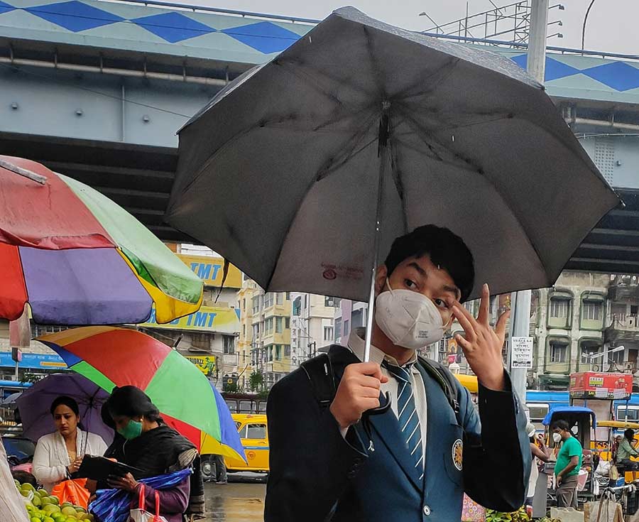 A masked student waits for his commute to school on VIP Road. Schools, colleges and universities in Bengal reopened on Thursday