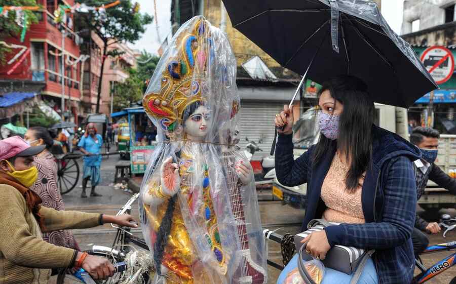 A woman takes a Saraswati idol home on Friday morning near Kumartuli