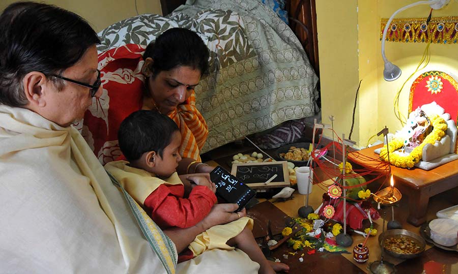 An elderly teaches the first alphabets to a child on a Tab and a traditional slate in a ceremony called ‘haate khori’ during Saraswati Puja celebrations at a north Kolkata residence. 
