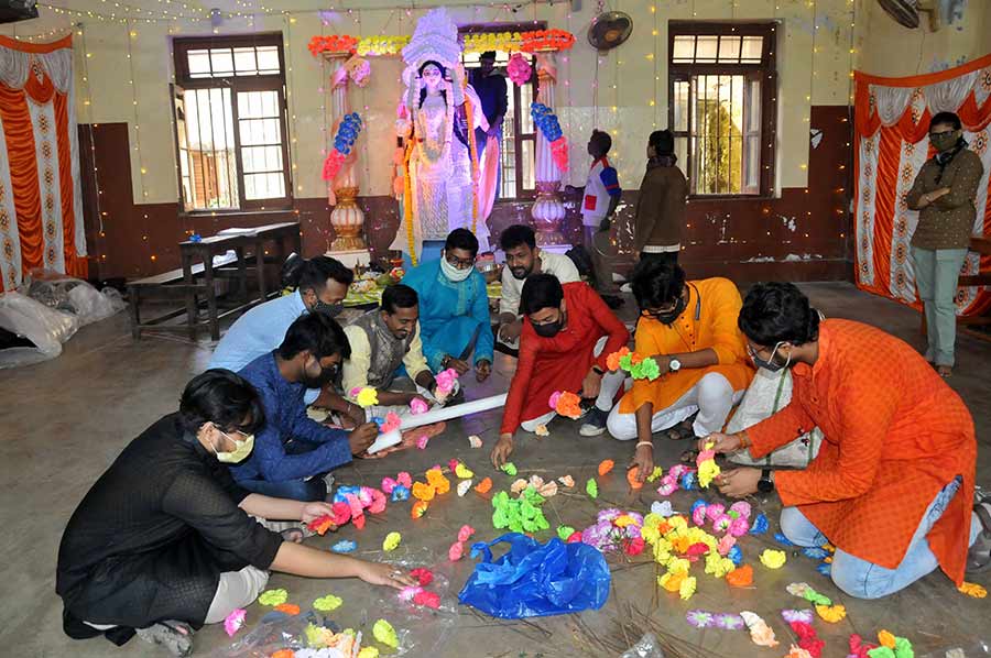 Students of Maharaja Manindra Chandra College string together artificial flowers into garlands for decorating the goddess and the venue of the puja. 
