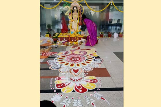 A sprawling alpana in front of the Saraswati idol at the Heritage Institute of Technology as a student seeks blessings from the Goddess.