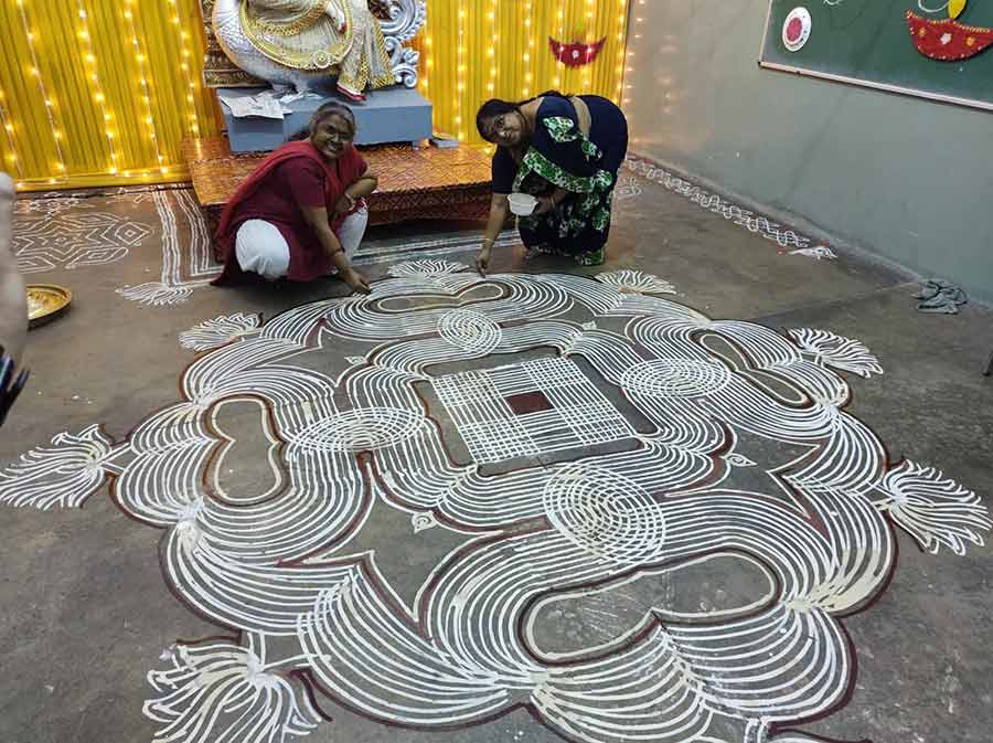 Teachers of a school in south Kolkata draw an intricate ‘kolam’ at the venue of the Saraswati Puja. 
