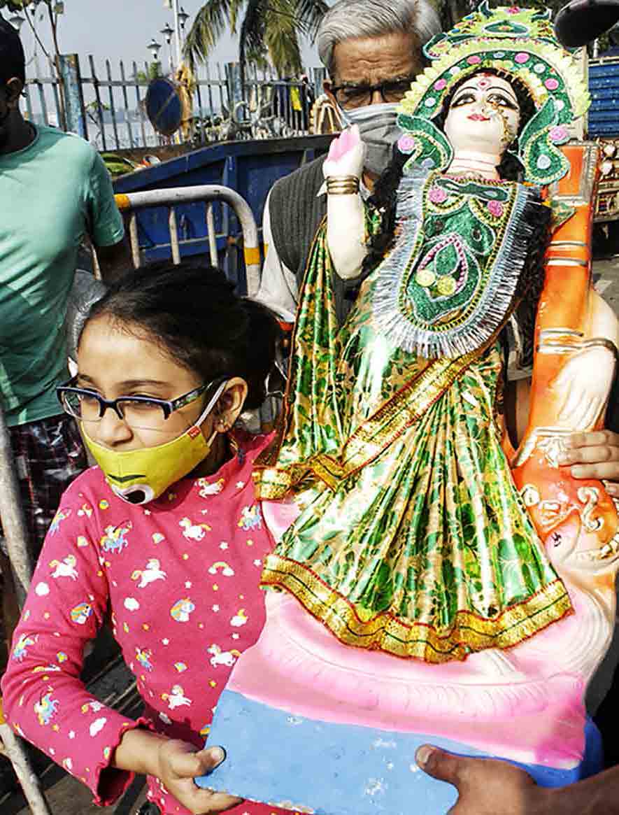 A young girl carries a Saraswati idol at Judges Ghat in central Kolkata for immersion on Sunday