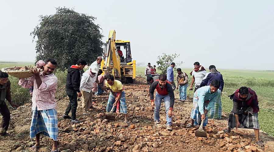 Residents of Dabtipara, one of the seven villages that collected funds, in Murshidabad district, repair the dilapidated road on Wednesday.