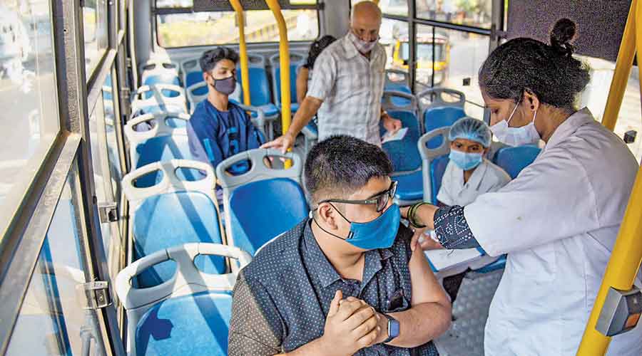 A health official administers a dose of Covid-19  vaccine to a passenger in  Navi Mumbai.
