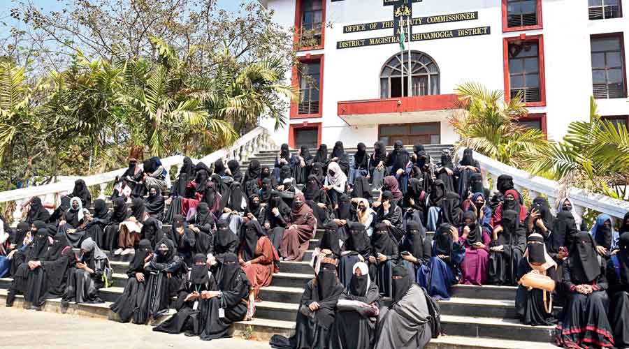 Students wearing burqa and hijab sit in protest outside the Shimoga district collector’s office on Thursday.