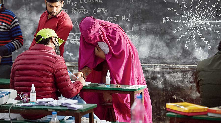 A Muslim woman registers her name before casting vote at a polling booth, during the first phase of Uttar Pradesh Assembly elections, in Kairana, Thursday, Feb. 10, 2022. 