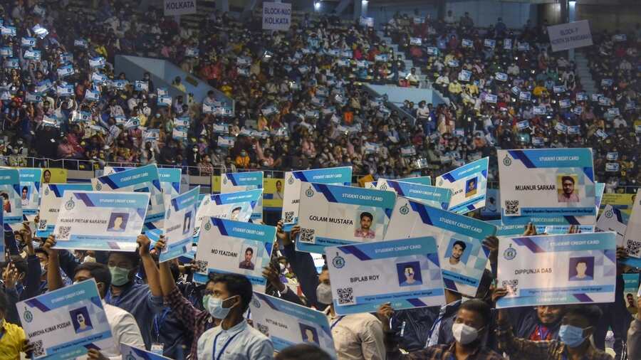 Students wave credit cards given by the state government for pursuing higher education, at Netaji Indoor Stadium in Kolkata on Thursday. 