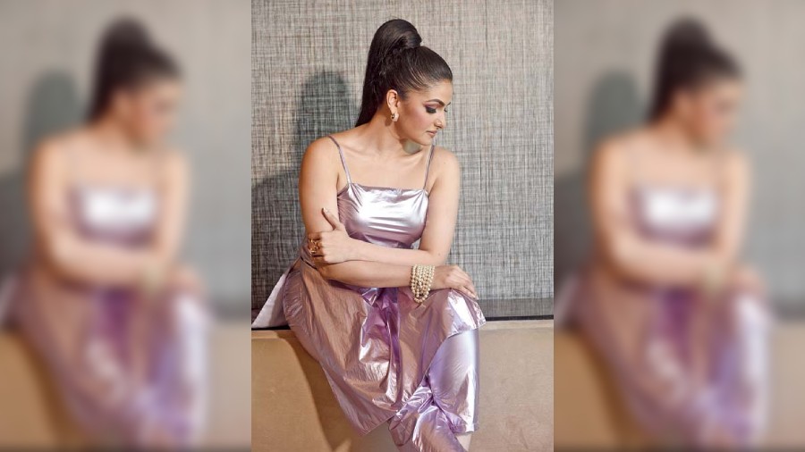 For the Y2K metal trend look, Tnusree posed charming in a lustrous lavender co-ord set featuring a quarter-length pair of slim-fit pants and a long noodle-strap top from Couche. It is accessorised with a pearl neckpiece from Lashkara by Ritu Dhingra, worn as a bracelet on the hand. The hair tied into a high ponytail, dramatic  glittery eyes and semi nude lips complete the look.