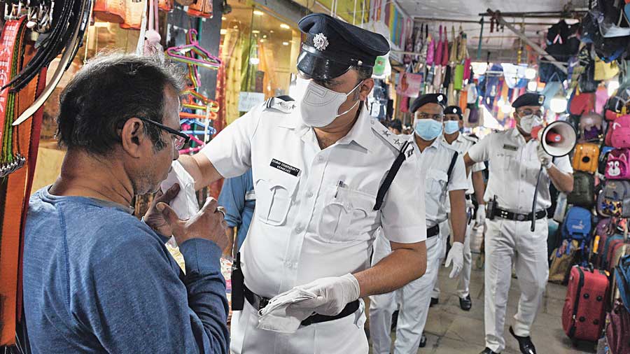 Police hand masks to people in Gariahat on Friday afternoon.