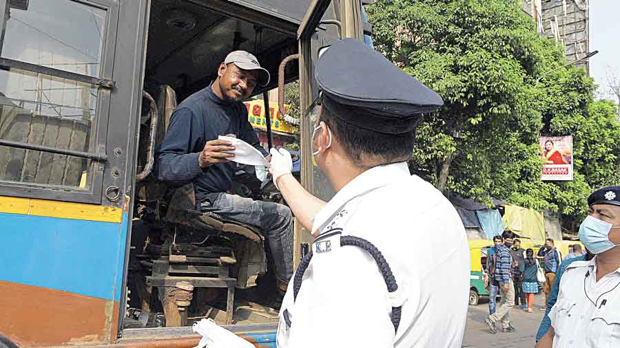A cop gives a mask to a bus driver in Gariahat .