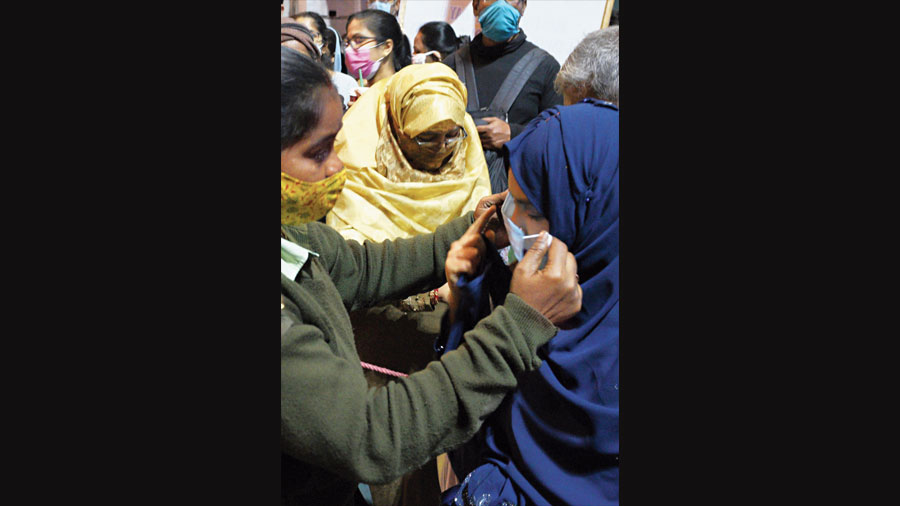 A civic volunteer hands a mask to a woman on Park Street on Friday.