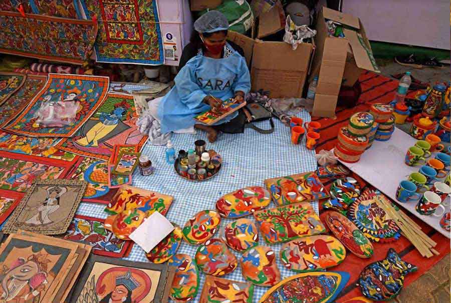 RAINBOW CRAFT: A masked artisan paints a ‘patachitra’ on a knick-knack at Saras Mela on Wednesday, December 29. Organised by the West Bengal government at the New Town Mela ground, the fair will continue till January 3. 