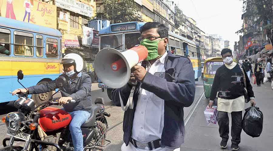 A policeman makes announcements on a loudhailer, asking commuters to wear masks and maintain other Covid norms in Burrabazar on Wednesday.