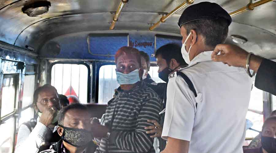 Policemen board buses in Burrabazar to check whether passengers have their masks on.