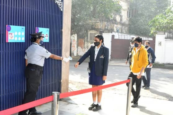 Students maintain distance and get their temperature checked before entering the campus. 