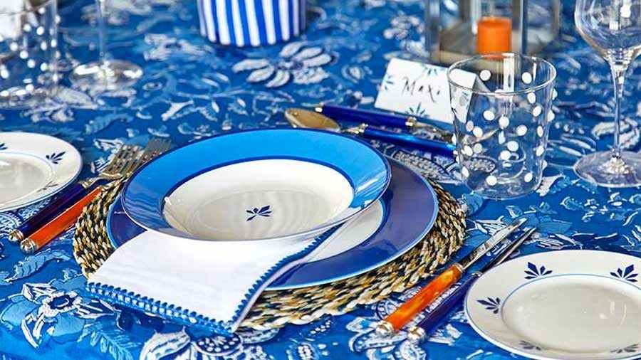 A tablescape featuring a white and blue palette, accented by pops of orange and dotty glassware
