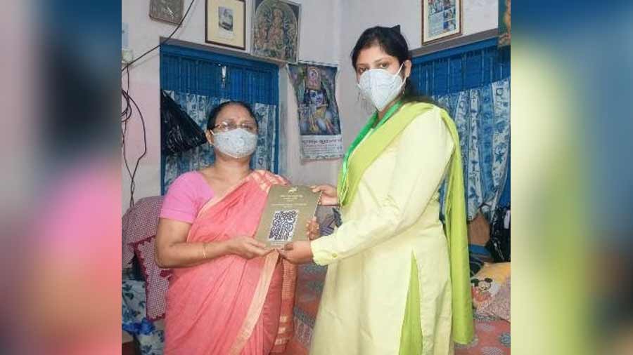 A copy of The Bengal magazine is presented to a Pronam member during one of Pronam’s regular in-person visits to the houses of senior citizens