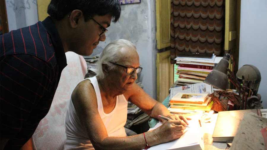 Mukherjee looks on as Debnath signs his book