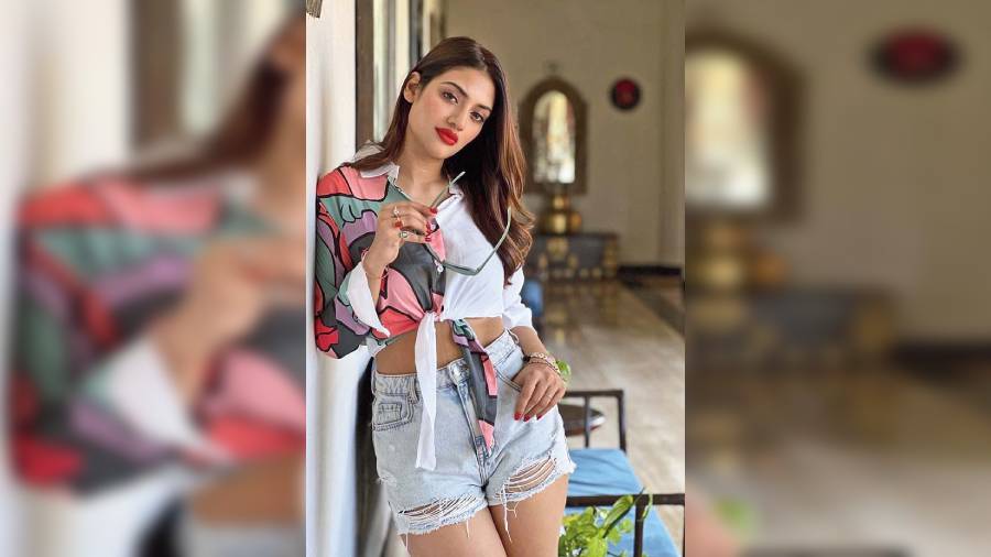 Ripped denim shorts, quirky knotted white shirt, bold red puckers, bright red nails and a stack of wristbands — new mom Nusrat Jahan had her beach vacay OOTD on point!