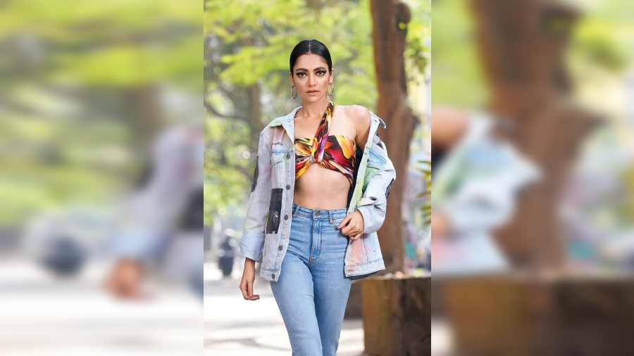 The transeasonal baggy denim look is stylised with a multicoloured modal fabric scarf from Sasya, wrapped as a one-shoulder tube top. Magenta block shades on the eyes, the hair tied up into a neat middle-parted bun, pink on the lips and cheek completed this street-style smart look.