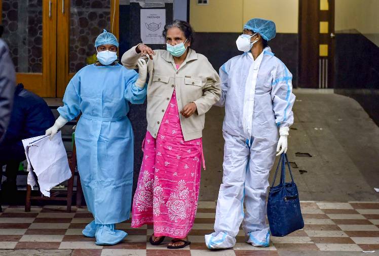 Health workers help a patient after her discharge from a state government-run COVID-19 hospital, in Kolkata. Physicians believe that comorbidity could be one of the explanations for the high death rate