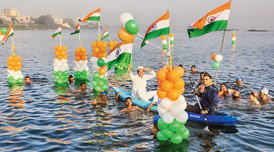 People hold the national flags as they swim in the Tapi river to celebrate Republic Day, in Surat, Wednesday, January 26, 2022. 