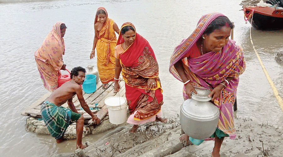 Homemakers on a boat on the Sundarika-Dewaniya river to fetch water.