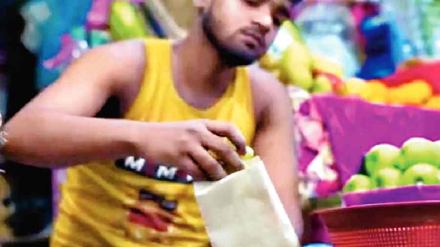 A shopkeeper packs fruits  in a paper bag at the New Town market