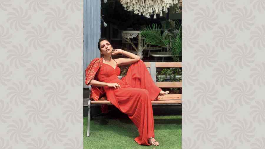 Susmita posed for a festive look in this red self-textured jumpsuit from Varnika Sangoi, styled with contemporary trends, like wide-legged silhouette, cut-out back and a bow tie. It is paired with a red and gold blazer to elevate the smart look.