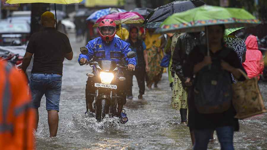 People wade through a water-logged street following monsoon rains, in Mumbai